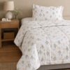 Cubrecama blanco con estampado floral beige sobre una cama