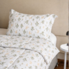Cubrecama blanco con estampado floral beige sobre una cama