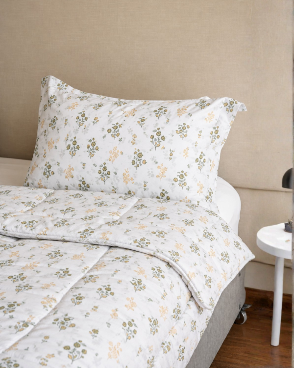Cubrecama blanco con estampado floral beige sobre una cama