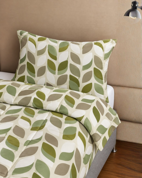 Cubrecama crema con estampado floral verde sobre una cama