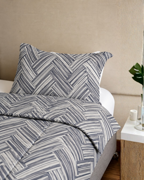 Cubrecama gris con estampado líneas hueso sobre una cama