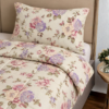 Cubrecama crema con estampado floral lila sobre una cama