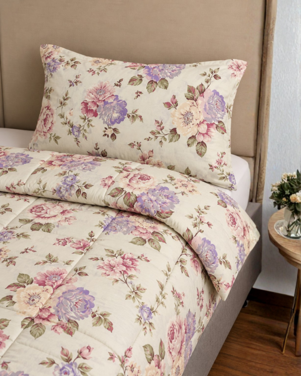 Cubrecama crema con estampado floral lila sobre una cama