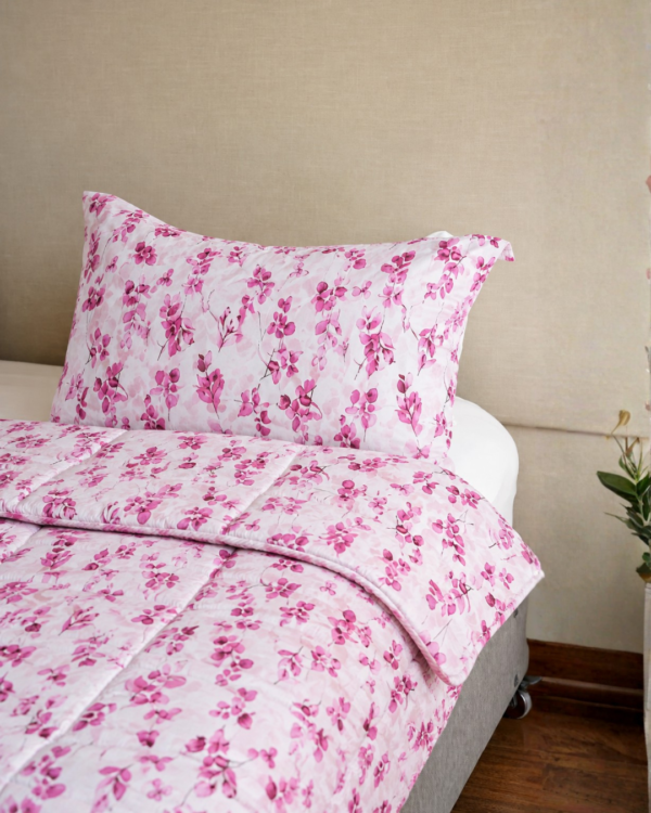 Cubrecama rosado con estampado floral fucsia sobre una cama
