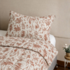 Cubrecama hueso con estampado floral terracota sobre una cama