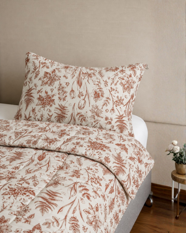 Cubrecama hueso con estampado floral terracota sobre una cama