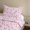 Cubrecama rosado con estampado floral rojo sobre una cama