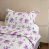 Cubrecama hueso con estampado floral morado sobre una cama