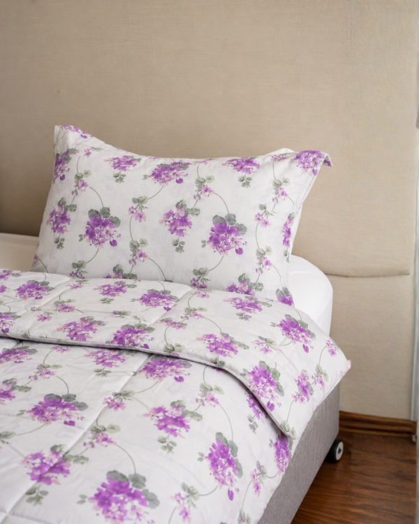 Cubrecama hueso con estampado floral morado sobre una cama
