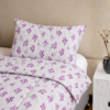 Cubrecama hueso con estampado floral lila sobre una cama
