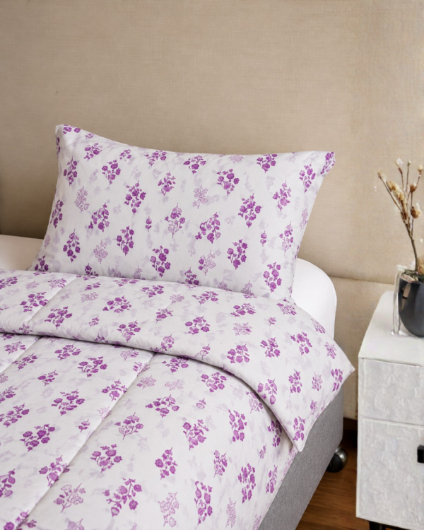 Cubrecama hueso con estampado floral lila sobre una cama