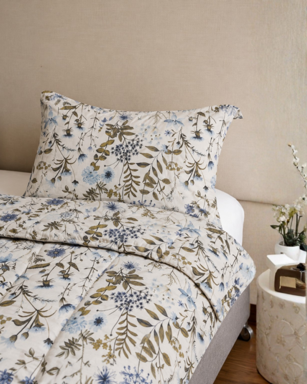 Cubrecama hueso con estampado floral verde sobre una cama