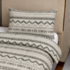 Cubrecama hueso con estampado tribu gris sobre una cama