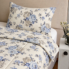 Cubrecama hueso con estampado floral celeste sobre una cama
