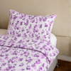 Cubrecama lila con estampado floral púrpura sobre una cama