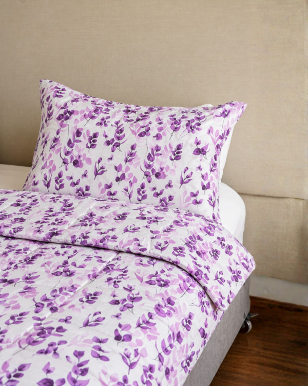 Cubrecama lila con estampado floral púrpura sobre una cama