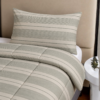 Cubrecama gris con estampado líneal sobre una cama