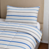 Cubrecama blanco con estampado líneal turquesa sobre una cama