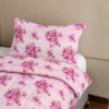 Cubrecama rosado con estampado flores fucsia sobre una cama