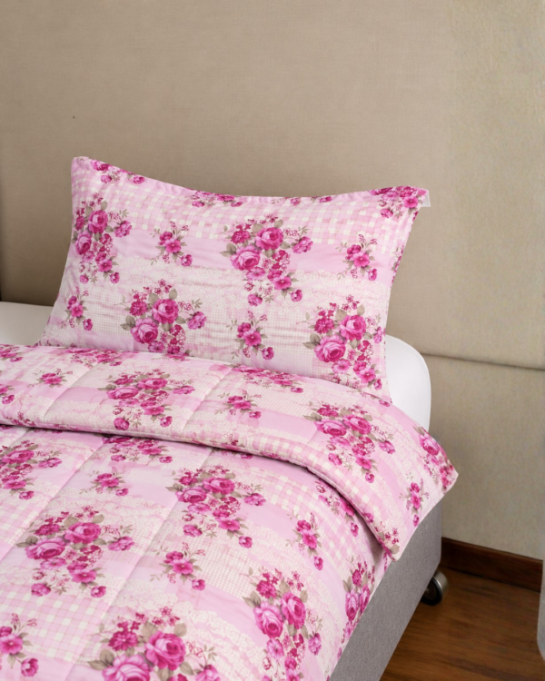 Cubrecama rosado con estampado flores fucsia sobre una cama