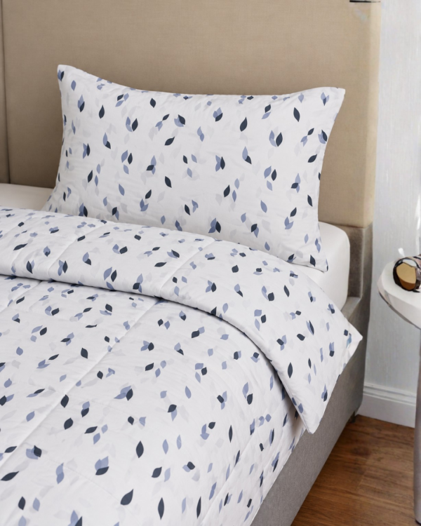 Cubrecama blanco con estampado triángulos chiquitas color azul sobre una cama
