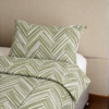 Cubrecama verde con estampado líneas nude sobre una cama