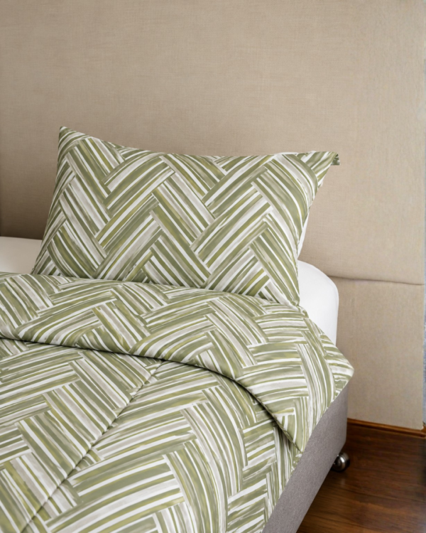 Cubrecama verde con estampado líneas nude sobre una cama