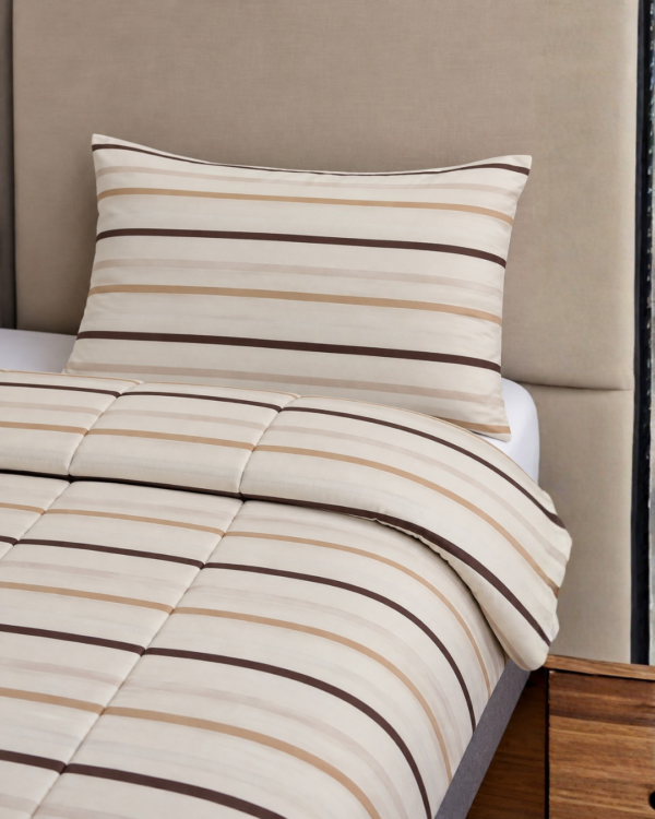 Cubrecama beige con estampado líneas marrones sobre una cama