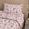 Cubrecama hueso con estampado flores guinda sobre una cama
