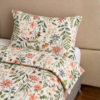 Cubrecama nude con estampado flores naranjas sobre una cama