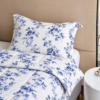 Cubrecama blanco con estampado flores azules sobre una cama