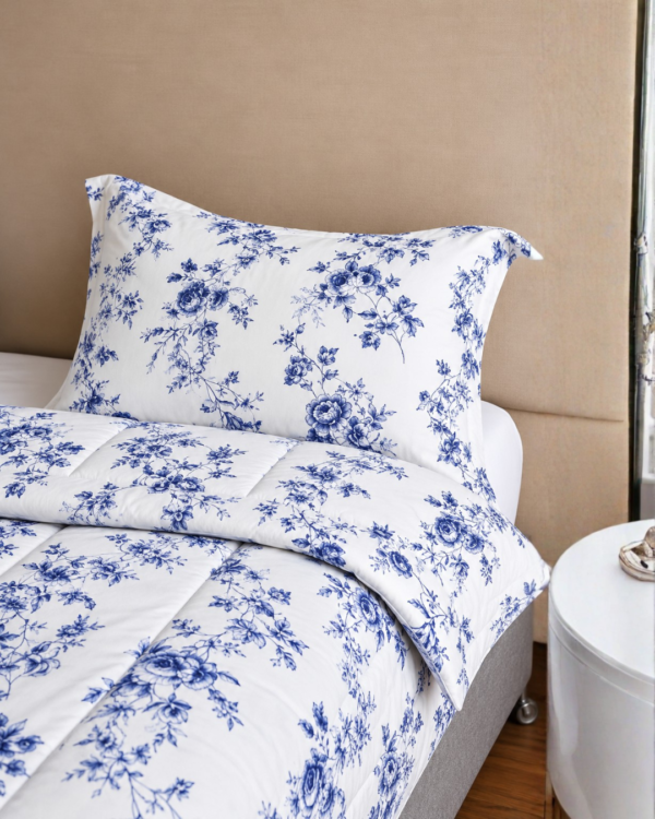 Cubrecama blanco con estampado flores azules sobre una cama