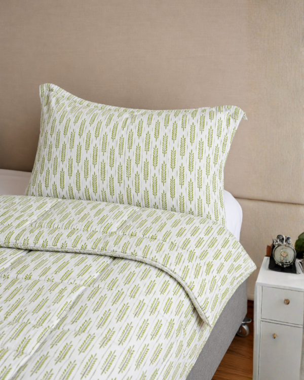 Cubrecama blanco con estampado espiga verde sobre una cama