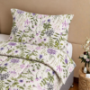 Cubrecama hueso con estampado floral lila sobre una cama