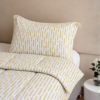 Cubrecama blanco con estampado espiga dorada sobre una cama