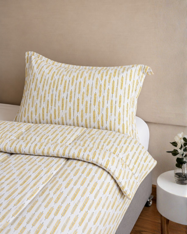 Cubrecama blanco con estampado espiga dorada sobre una cama