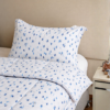 Cubrecama blanco con estampado triángulos chiquitas color azulino sobre una cama
