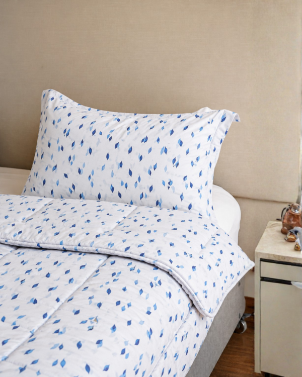 Cubrecama blanco con estampado triángulos chiquitas color azulino sobre una cama