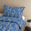 Cubrecama color azul jean con estampado de ramas mostazas sobre una cama