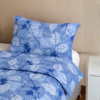 Cubrecama azul con estampado hojas celestes sobre una cama