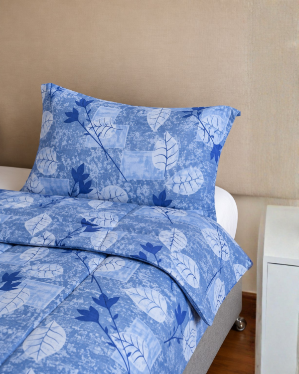 Cubrecama azul con estampado hojas celestes sobre una cama
