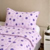 Cubrecama lila con estampado floral violeta sobre una cama
