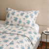 Cubrecama hueso con estampado floral color agua marina sobre una cama