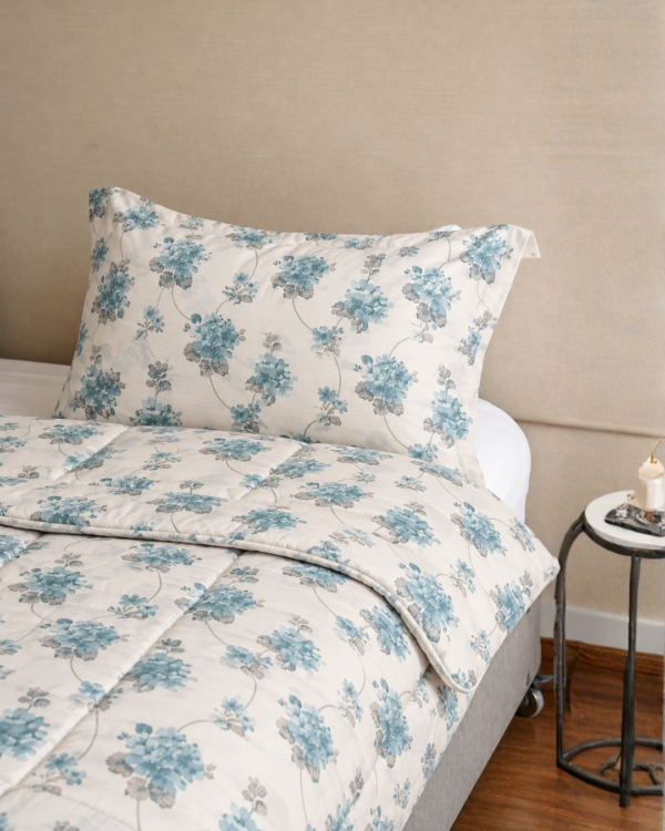 Cubrecama hueso con estampado floral color agua marina sobre una cama