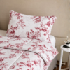 Cubrecama blanco con estampado floral rojo sobre una cama