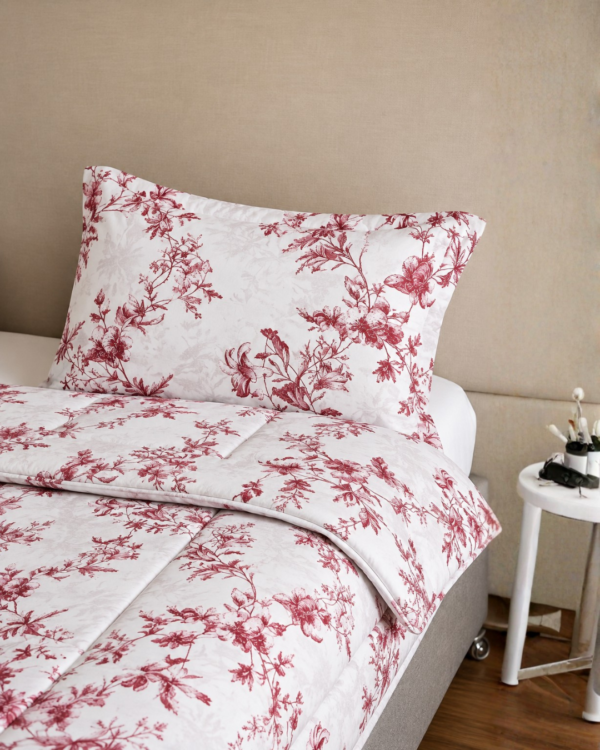 Cubrecama blanco con estampado floral rojo sobre una cama